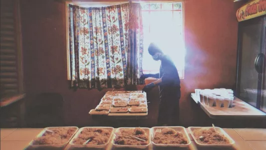 DEVI MACHETE - At the start of the COVID-19 pandemic, a CVYM volunteer is wearing protective gloves and a face mask to serve meals to-go out of the window. June 4, 2020. Tijuana, Mexico.