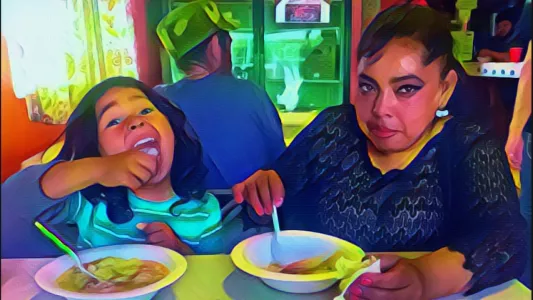 DEVI MACHETE - Inside the dining area, a migrant mother and her little boy pose for a picture as they eat hot chicken noodle soups. July 9, 2019. Tijuana, Mexico.