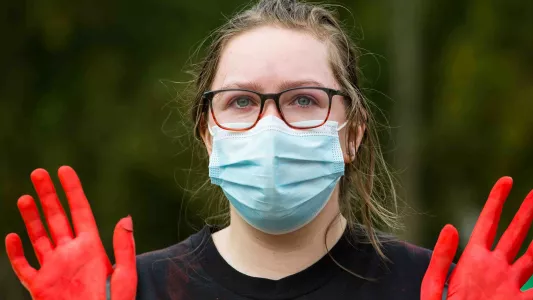 sam davis. Animal and climate justice protestor with tearful eyes and red dyed hands at Parliament Square, London 2020